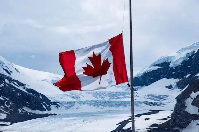 canada flag at a pole on mountain area