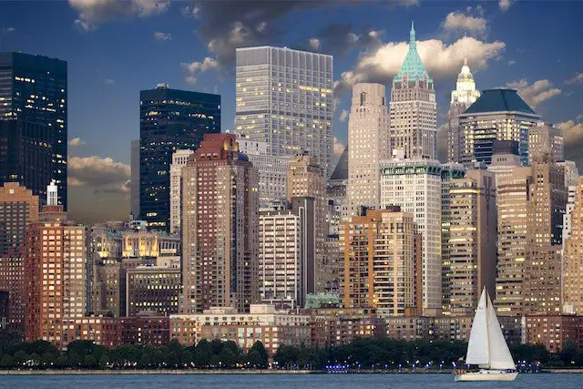 cityscape during night time near body of water and sail boat