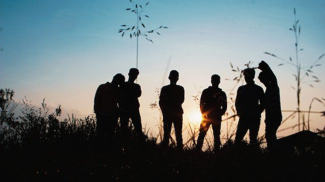 silhouette group of people standing on grass field