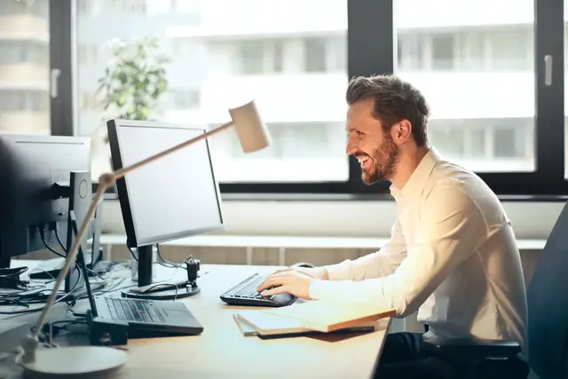 Pexels - Man in White Dress Shirt Sitting on Black Rolling Chair While Facing Black Computer Set and Smiling