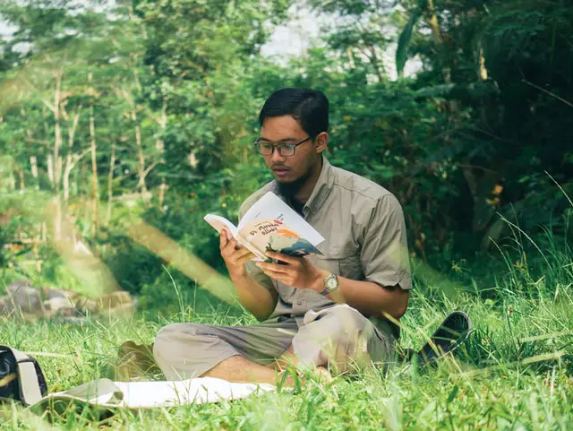 Man reading a book in a garden