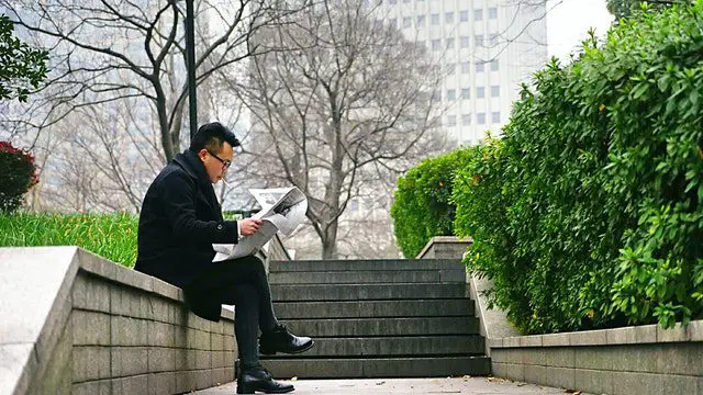Pexels - Man Reading Newspaper Sitting on Stair Wall
