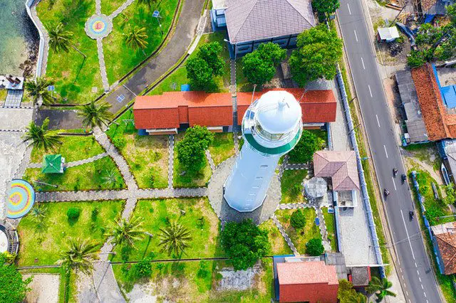 Aerial Photography of White Lighthouse Near Multicolored Houses and Green Field View