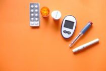 diabetic measurement tools and pills on orange background
