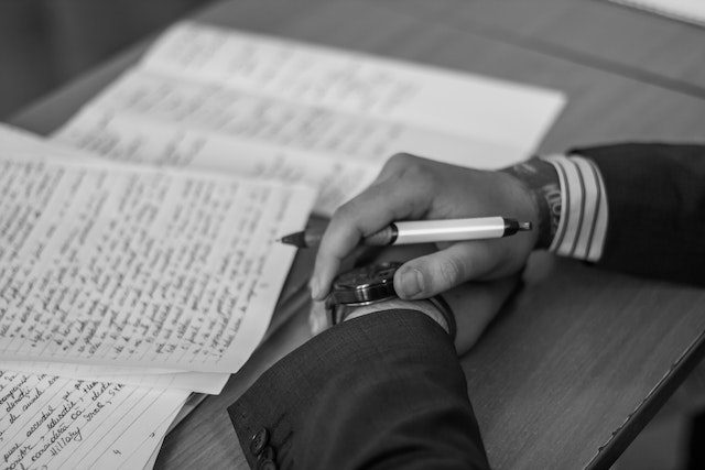 Person Holding Pen And Writing