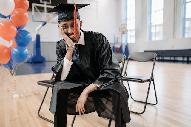 Pexels - Phtoto of a man sitting on a chair with graduation gown