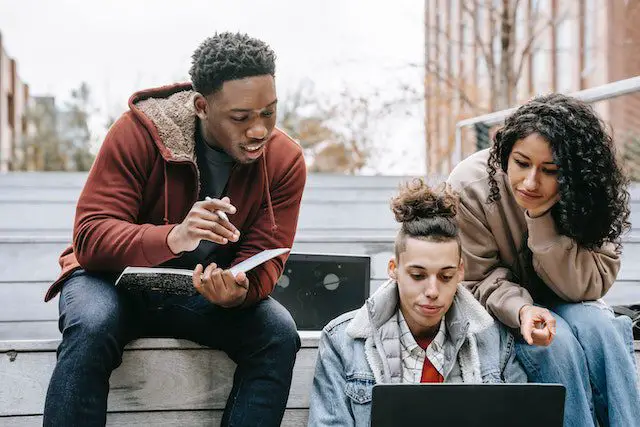 Pexels - Multiracial students studying on netbook with notebook on steps