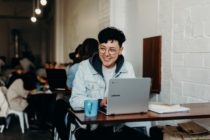 A smiling man sitting in a public space