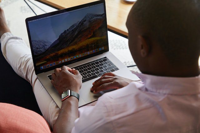 black man sitting with laptop on his lap.