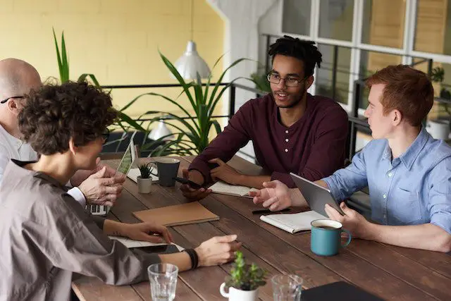 Pexels - photo Of People Leaning On Wooden Table