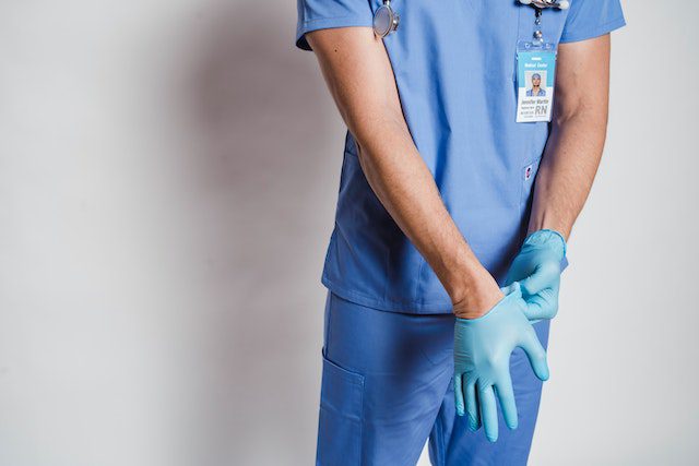 Male doctor putting on sterile gloves