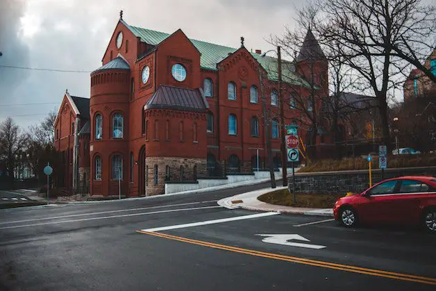 Red Car Parked Beside Brown Concrete Building