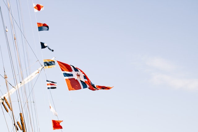 Pexels - Various flags waving on rope against blue sky