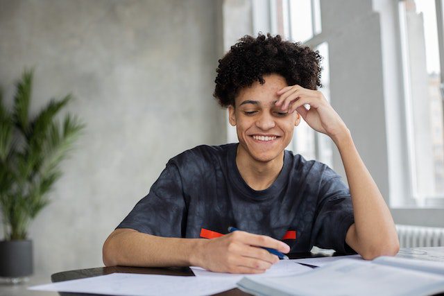 Cheerful black man writing on paper
