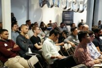 People sitting in an audience listening to a presentation at a conference