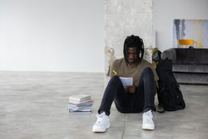 Black man writing in notebook while doing homework