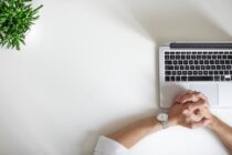 Unsplash - Hand on a desk with laptop nearby