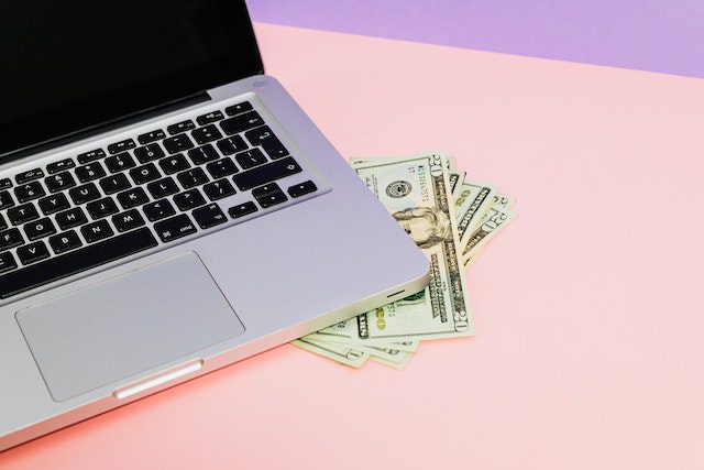Silver Laptop with US Dollar Bills