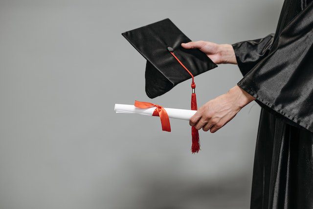 photo of person holding graduation cap and diploma