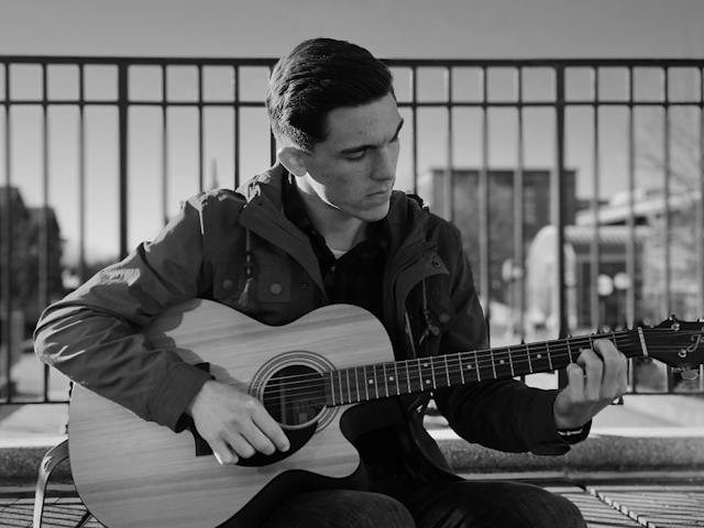 monochrome photo of man holding guitar