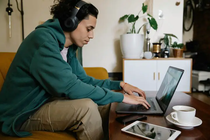 student sitting in front of laptop with his headphones on his ears