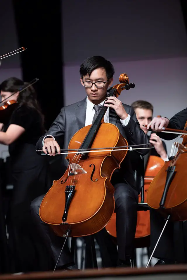 man in an orchestra playing the cello