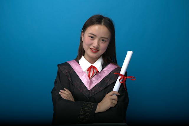 smiling graduate holding diploma on blue background