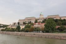 a large building sitting on top of a hill next to a river
