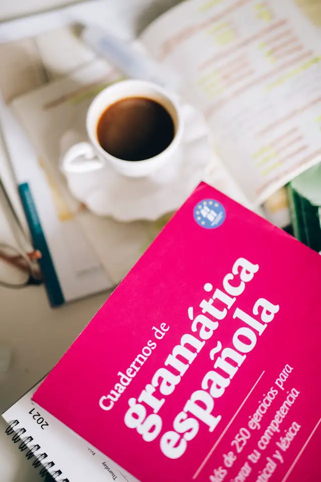 a spanish grammar on a 2021 desk calendar beside a cup of coffee