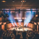 people standing on stage with lights turned on during nighttime