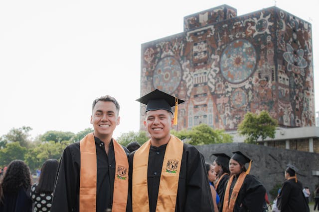 graduates posing with unam central library behind