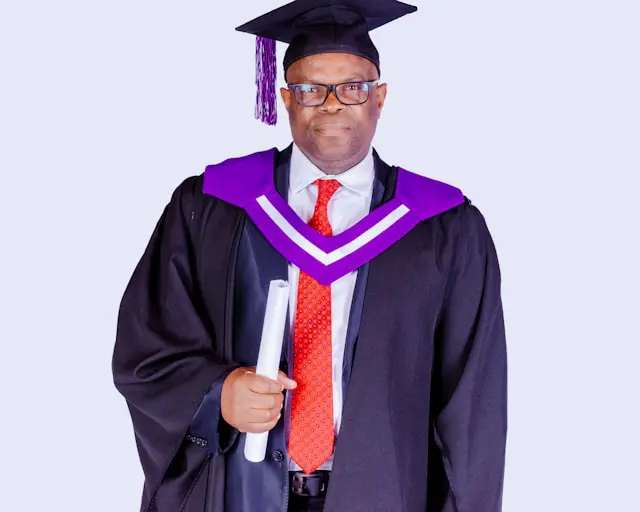 man in black academic dress wearing black academic hat