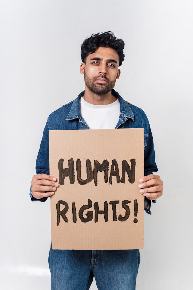 man in blue and white long sleeve shirt holding human rights text