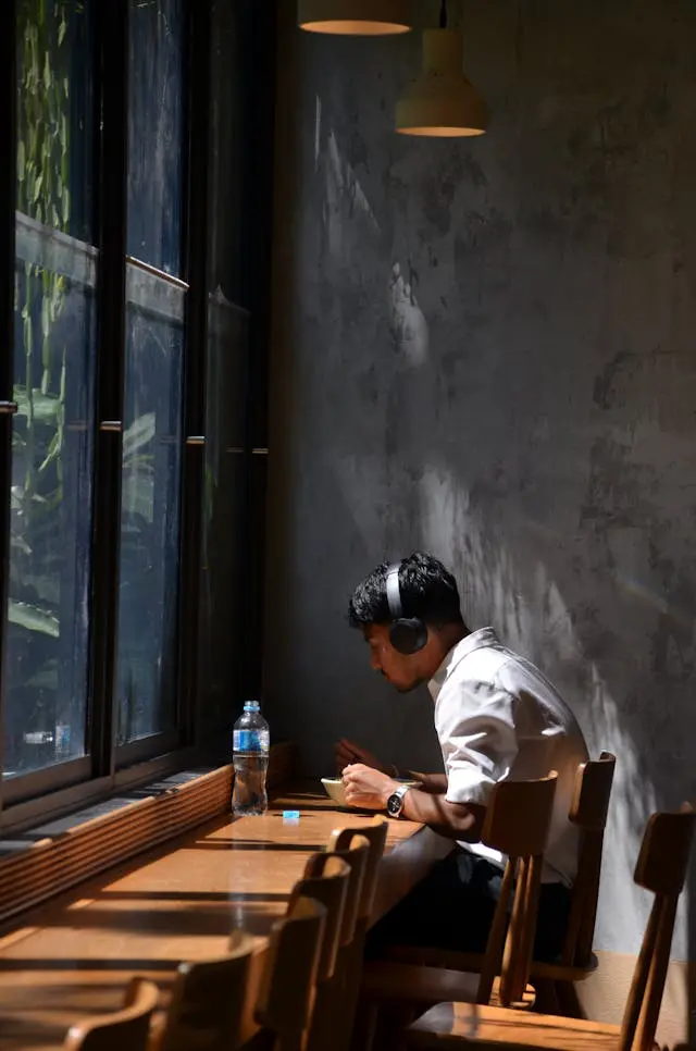 man in cafe working with headphones by window