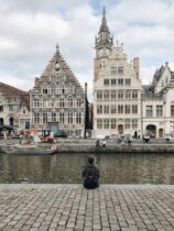 person sitting on pavement beside body of water