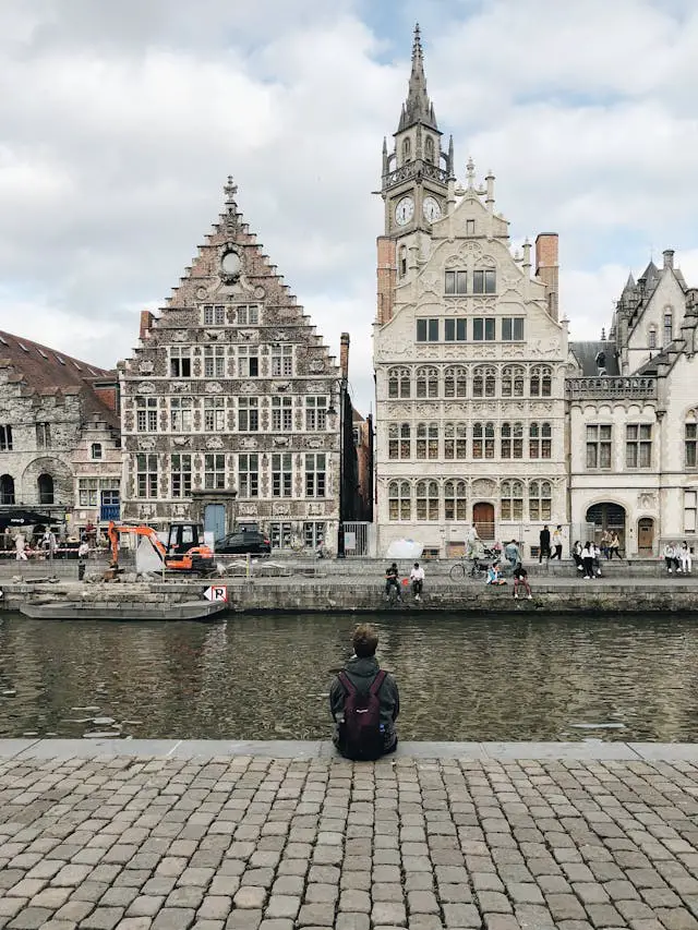 person sitting on pavement beside body of water