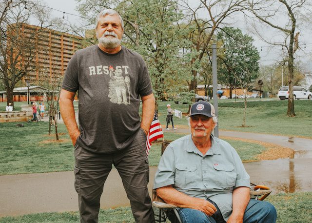 two men pose outside on a cloudy day