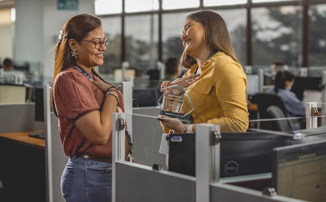 women talking in office holding trop