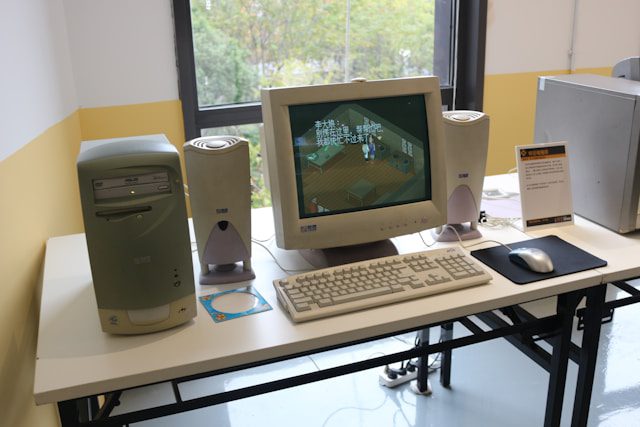 a desk with a monitor keyboard mouse and speakers