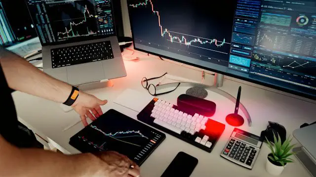 a man sitting at a desk with two monitors and a laptop
