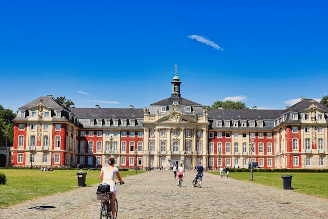 people bike in front of a large ornate building
