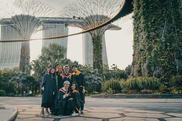 people in black academic dress standing on gray concrete pavement