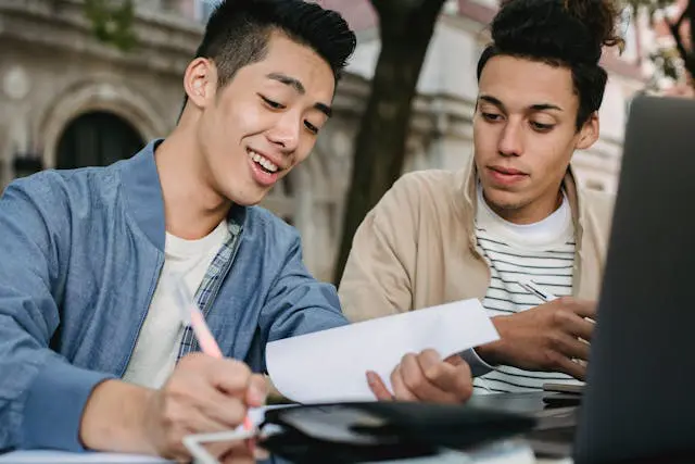 positive asian student doing homework with partner