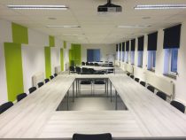 white wooden table and black chairs inside white green painted room