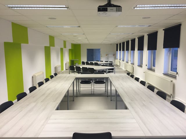 white wooden table and black chairs inside white green painted room