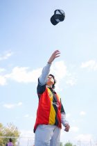 young man tossing hat in bright day outdoors