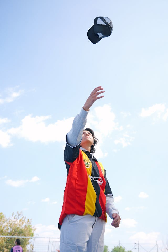 young man tossing hat in bright day outdoors
