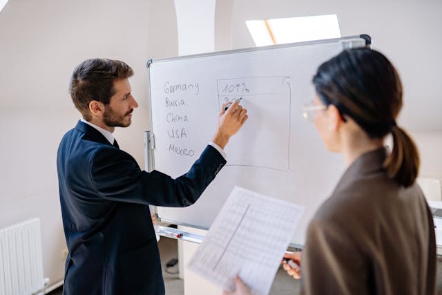man in blue suit writing on the whiteboard