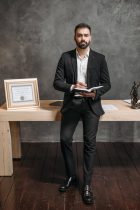person in black suit jacket holding a notebook