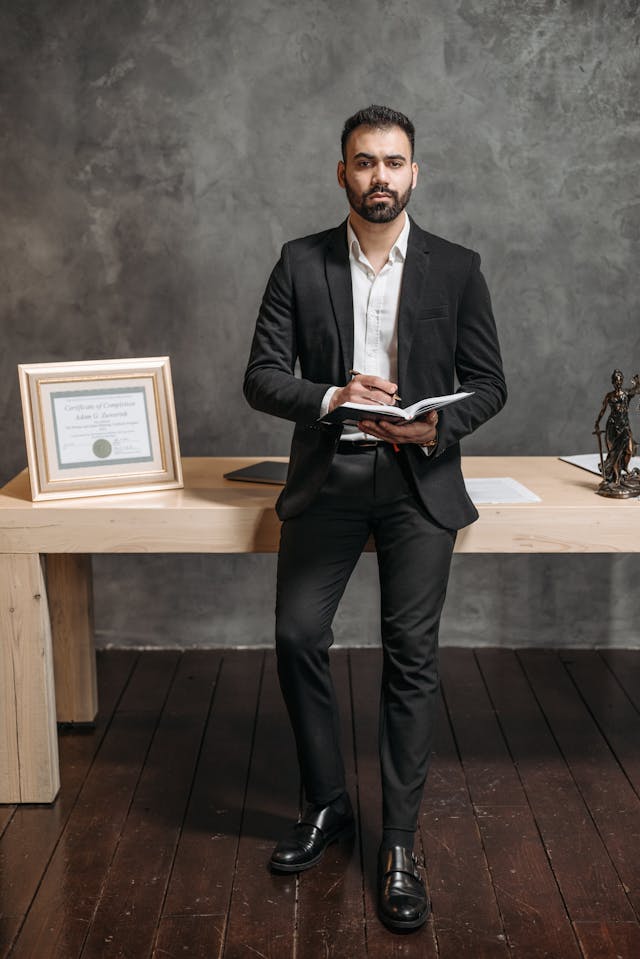 person in black suit jacket holding a notebook